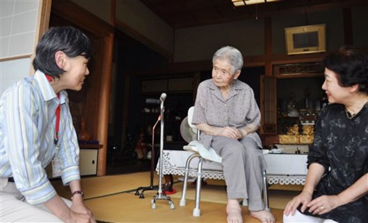 A Kobe city official, left, visits 100-year-old Mitsue Watase, center, at Watase's home on Tuesday. Officials started a door-to-door survey on the whereabouts of centenarians.
